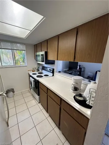 Kitchen with stainless steel range oven and light tile patterned flooring