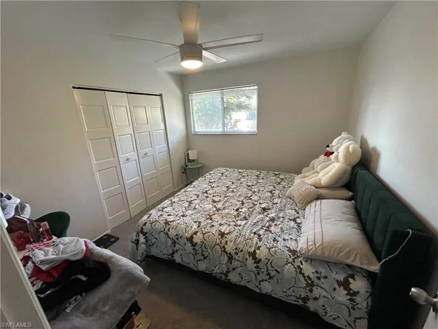 Bedroom featuring dark colored carpet, a closet, and ceiling fan