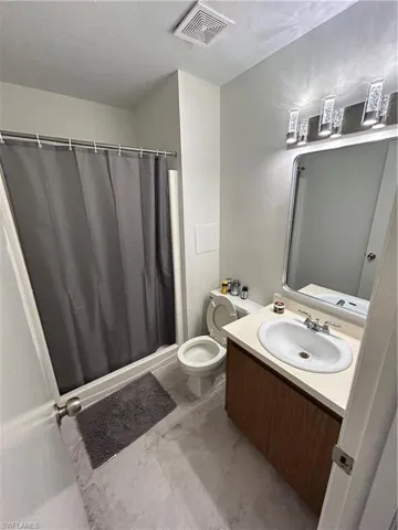 Bathroom featuring vanity, walk in shower, and toilet