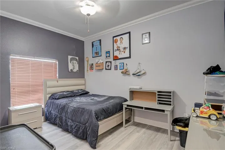 Bedroom featuring ornamental molding, light wood-style flooring, and a ceiling fan