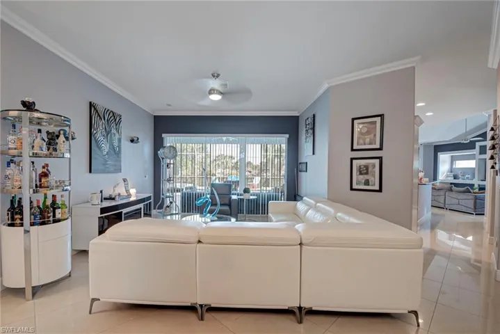 Living area with crown molding, a ceiling fan, and light tile patterned floors