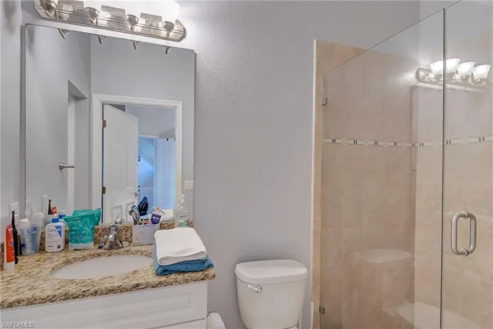 Full bath featuring a shower stall, vanity, and a textured wall
