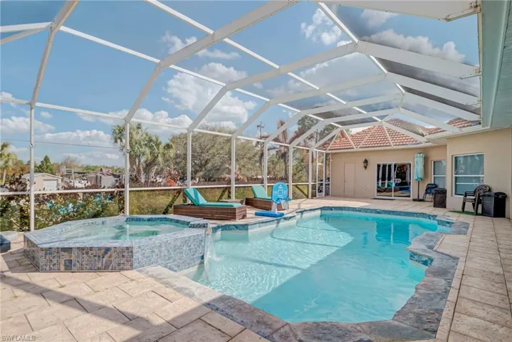 Integrated pool / spa featuring glass enclosure, a sunroom, and a patio area