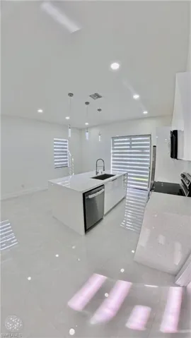 Kitchen featuring light stone countertops, hanging light fixtures, light tile patterned flooring, recessed lighting, and appliances with stainless steel finishes