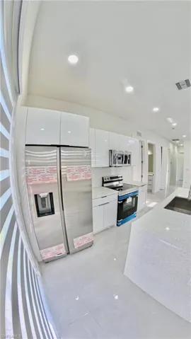 Kitchen with white cabinets, appliances with stainless steel finishes, recessed lighting, modern cabinets, and light stone countertops