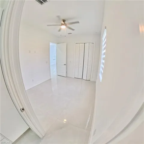 Unfurnished bedroom with light tile patterned floors, a closet, and a ceiling fan