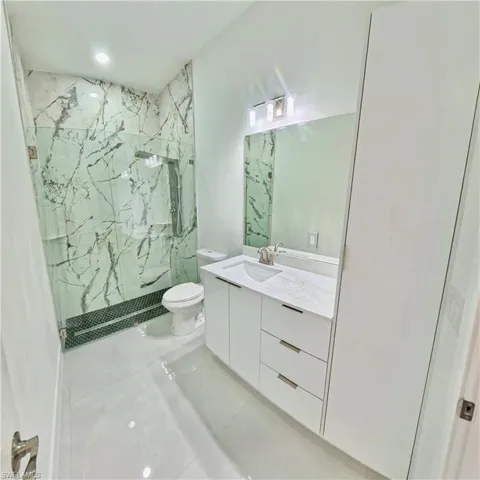 Full bath with a marble finish shower, vanity, and light tile patterned flooring