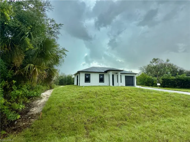 View of front of property featuring a front yard, stucco siding, a garage, and driveway