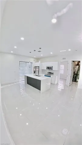 Kitchen with white cabinetry, decorative light fixtures, an island with sink, appliances with stainless steel finishes, and recessed lighting