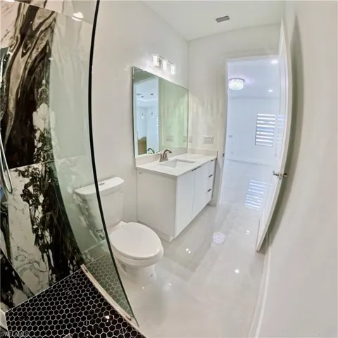 Bathroom featuring vanity, light tile patterned flooring, and a marble finish shower