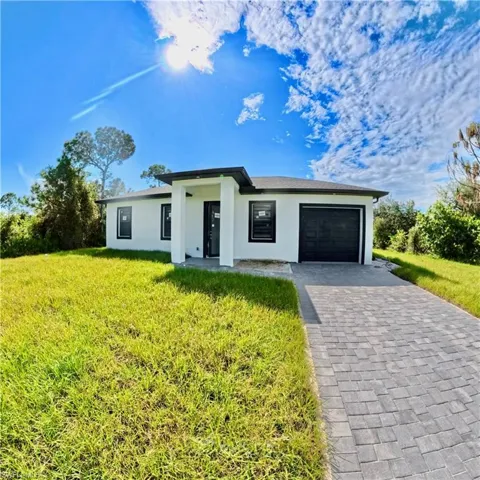 View of front of property featuring stucco siding, a garage, a front yard, and decorative driveway