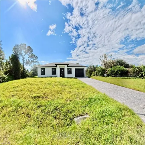 View of front facade featuring driveway, a front lawn, stucco siding, and an attached garage