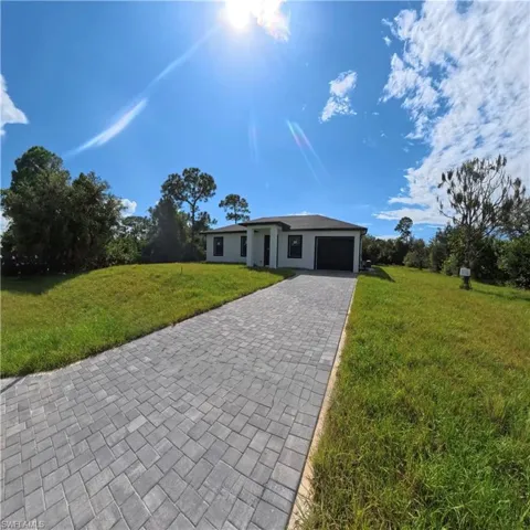 Ranch-style house with a front lawn, decorative driveway, and a garage