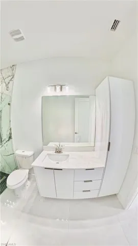 Full bathroom featuring vanity, a marble finish shower, and light tile patterned floors