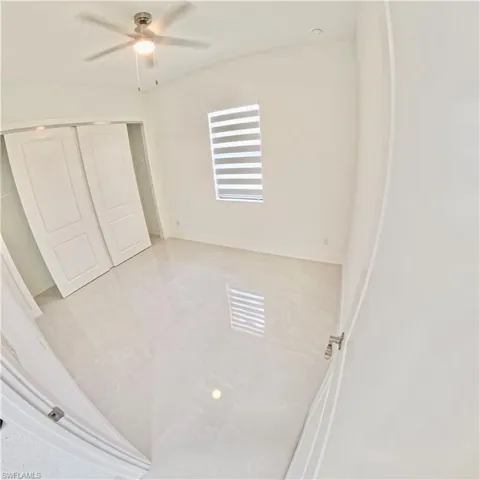 Unfurnished bedroom with ceiling fan, a closet, and tile patterned flooring