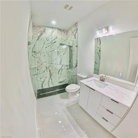 Bathroom with a marble finish shower, vanity, light tile patterned flooring, and recessed lighting