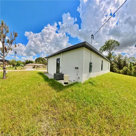 View of side of home with a lawn and stucco siding