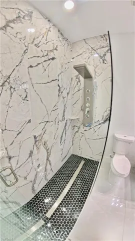 Full bath featuring a marble finish shower, tile patterned flooring, and recessed lighting