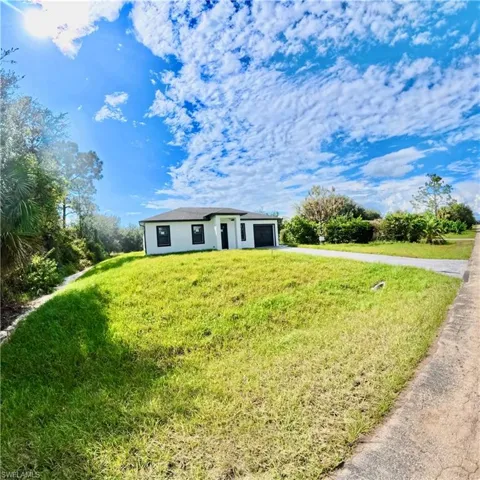 View of front of home with a front yard, stucco siding, driveway, and an attached garage