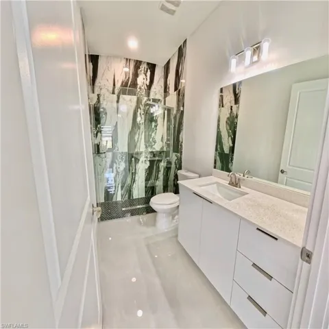 Full bathroom featuring a marble finish shower and vanity