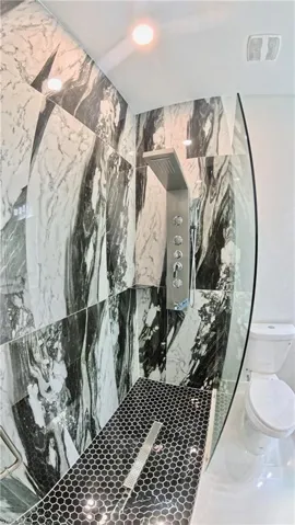 Bathroom view of a marble finish shower and toilet