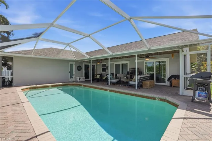Outdoor pool featuring an outdoor living space, a grill, a patio area, and screen enclosure