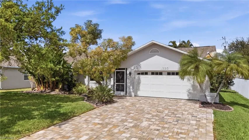 View of front of property with a front yard, a garage, decorative driveway, and stucco siding