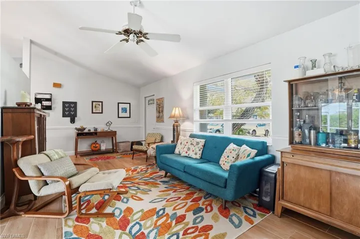 Living area featuring wood like tile floors, lofted ceiling, and a ceiling fan