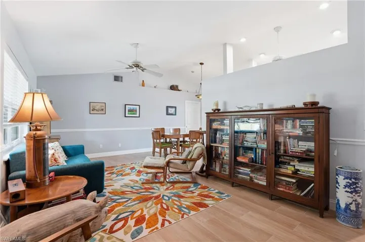 Living room featuring light wood tile floors, ceiling fan, and vaulted ceiling