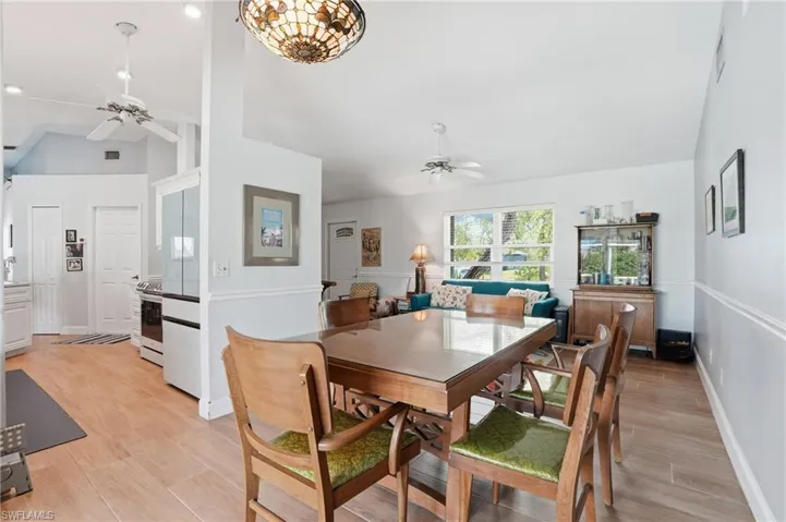 Dining space featuring a ceiling fan, light wood tile flooring, and lofted ceiling