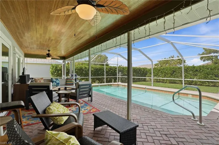Swimming pool featuring wooden ceiling, an outdoor lounge area, screen enclosure, and a grill