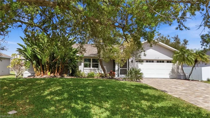 View of front of home featuring an attached garage, driveway, stucco siding, and a front yard