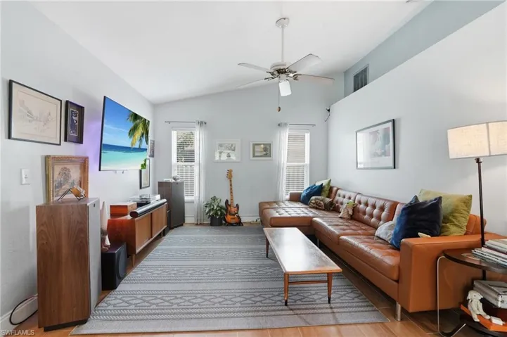 Living room featuring lofted ceiling, a ceiling fan, and light wood tile flooring