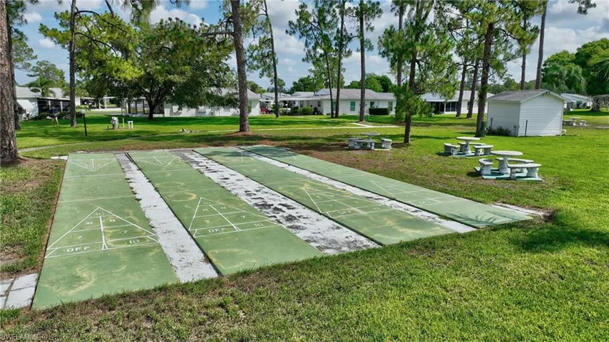 View of home's community featuring a lawn and shuffleboard
