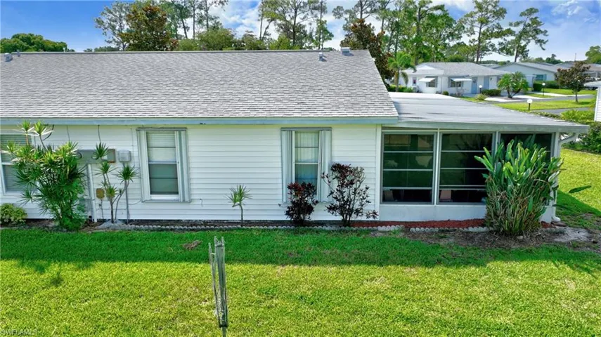 View of front of home with a front lawn, a shingled roof, and a sunroom