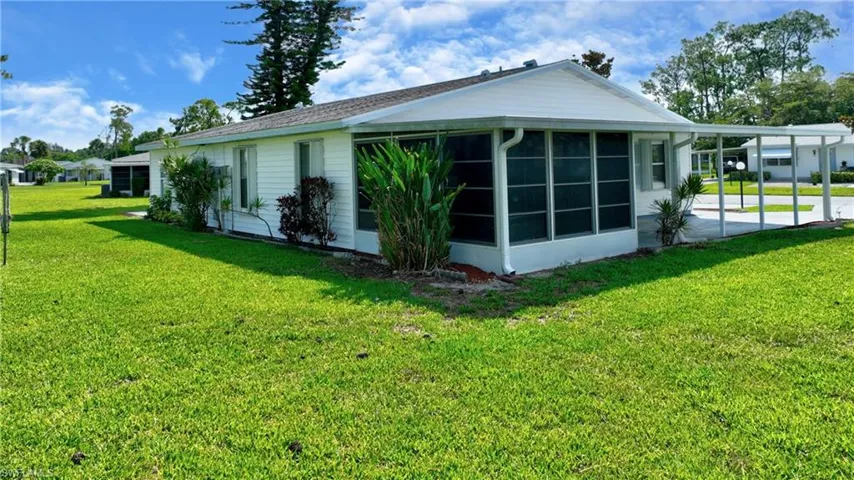 View of side of home with a sunroom, a yard, and an attached carport