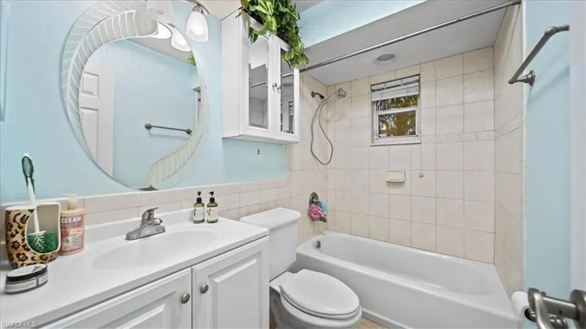 Full bath with shower / bath combination, vanity, and tile walls