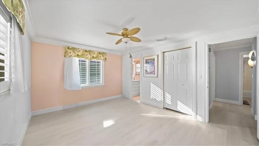 Unfurnished bedroom with light wood-style floors, ornamental molding, ceiling fan, and a closet