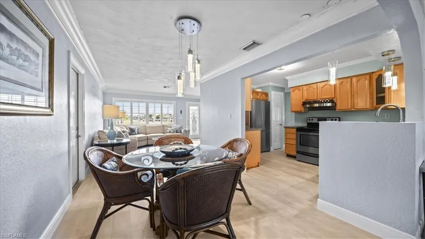 Dining area featuring a textured wall, crown molding, and light wood-type flooring