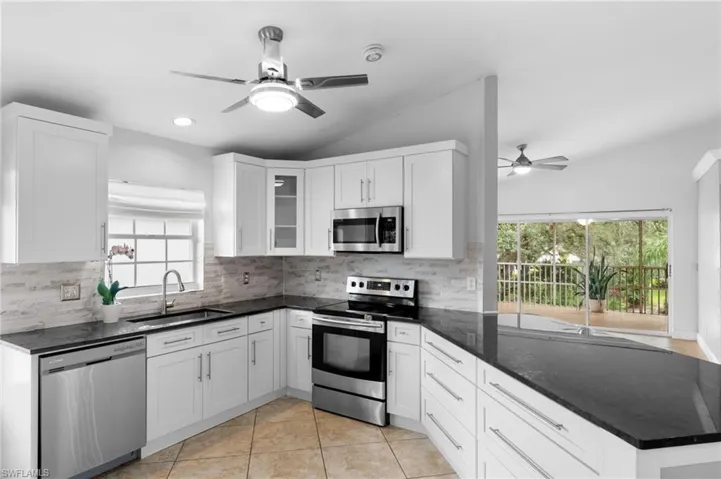 Kitchen featuring tasteful backsplash, stainless steel appliances, sink, light tile patterned flooring, and ceiling fan