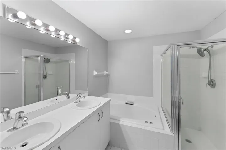 Bathroom featuring independent shower and bath and dual vanity