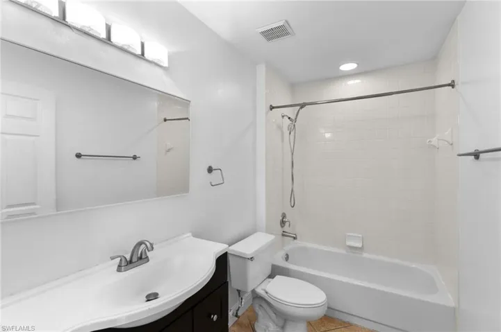 Full bathroom with tile patterned flooring, toilet, vanity, and tiled shower / bath