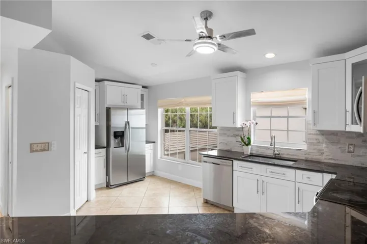Kitchen with white cabinets, stainless steel appliances, backsplash, and light tile patterned floors