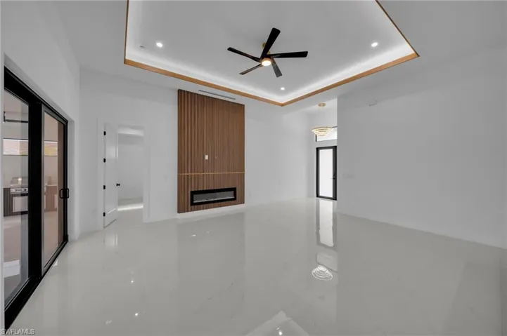 Unfurnished room with marble finish floor, a fireplace, and a raised ceiling