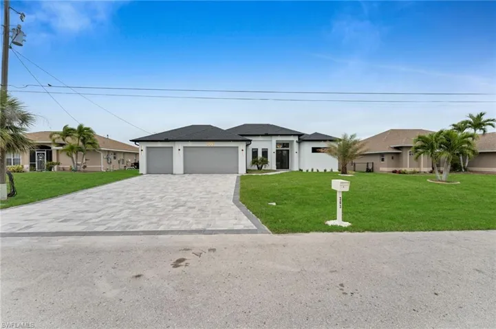 View of front of house with decorative driveway, a garage, a front lawn, and stucco siding