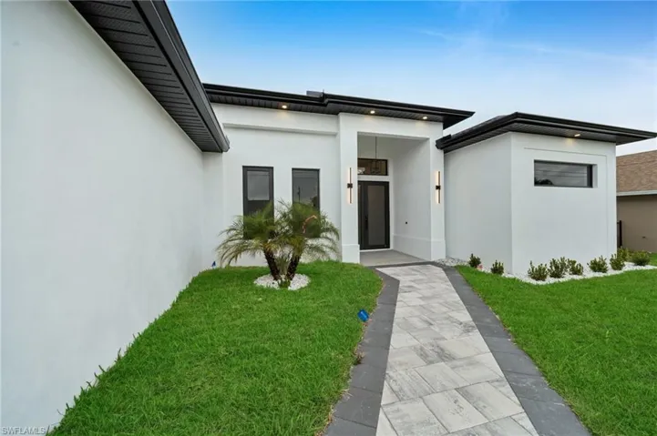 Doorway to property featuring stucco siding and a lawn