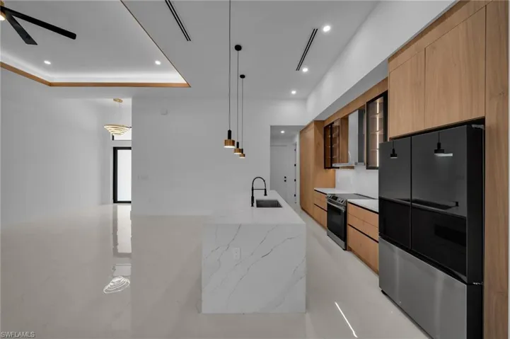 Kitchen with a sink, modern cabinets, freestanding refrigerator, and electric range oven