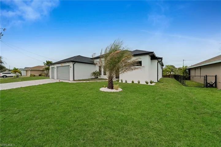 View of front of house with a front yard, fence, driveway, an attached garage, and stucco siding