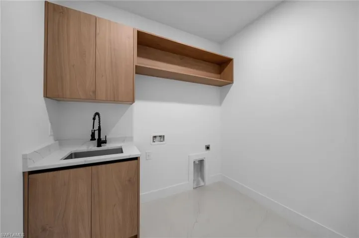 Laundry area with hookup for a washing machine, baseboards, hookup for an electric dryer, cabinet space, and a sink