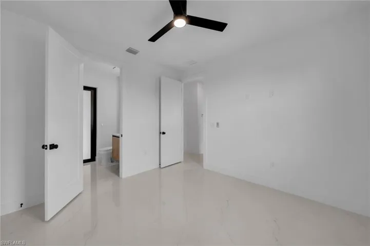 Unfurnished bedroom with visible vents, marble finish floor, a ceiling fan, connected bathroom, and baseboards